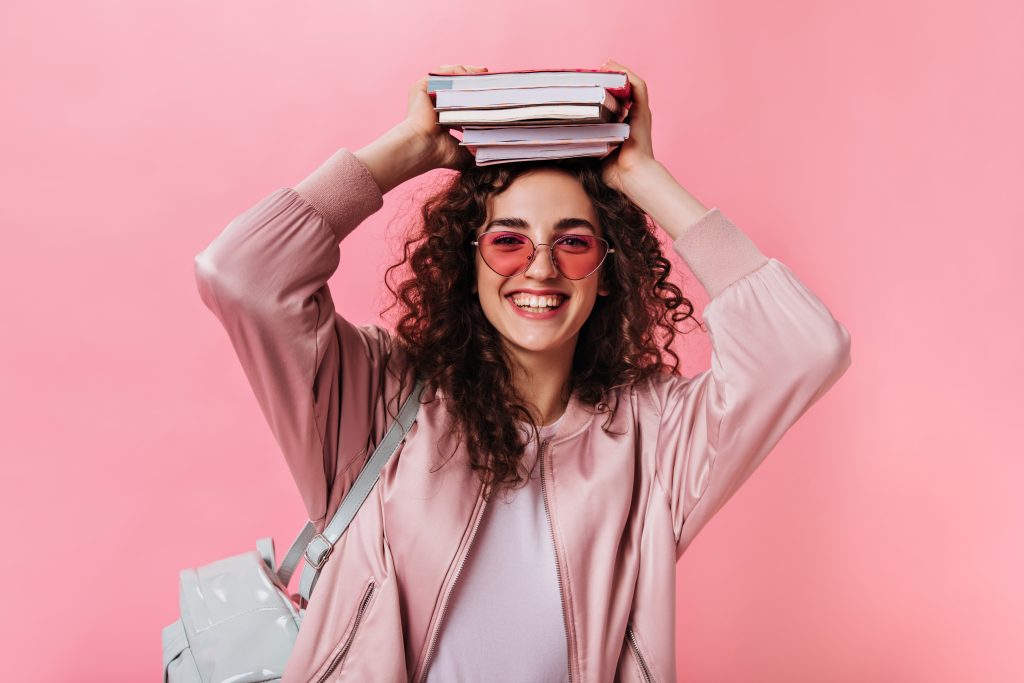 teenage woman pink outfit posing with books