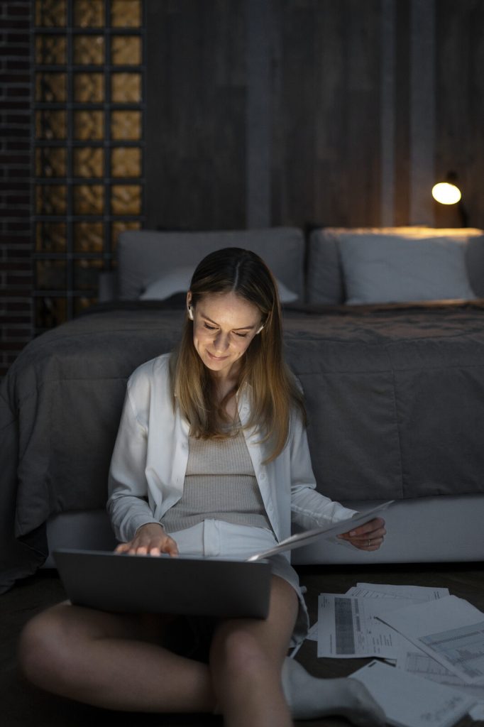 Opositora estudiando con el portátil sentada junto a la cama la noche antes del examen